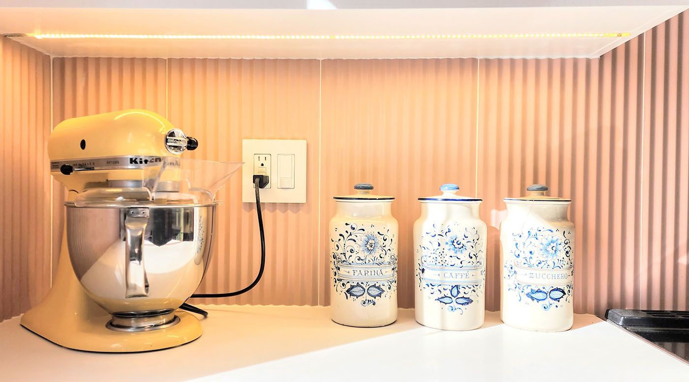 A kitchen counter with a mixer and three jars on it