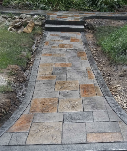 Stone pathway with central steps leading up through a grassy garden area