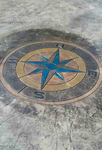 Blue-and-gold compass rose mosaic set into a concrete floor