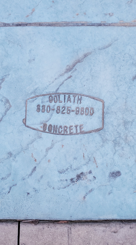 Blue concrete slab with stamped “Goliath 800-828-8888 Concrete” logo