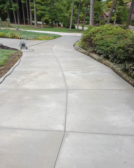 Curved concrete sidewalk through a landscaped park with trees and bushes
