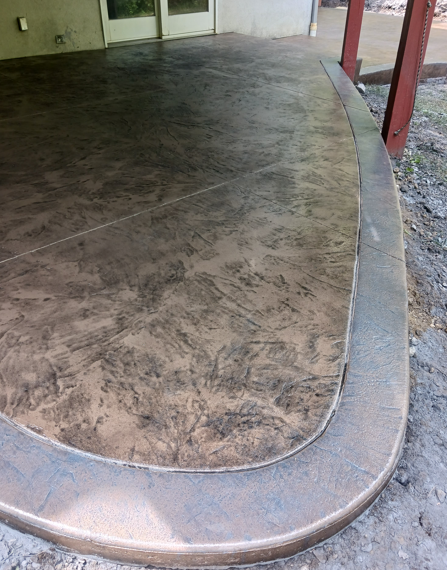 Curved concrete porch edge beside a dark stamped patio and building entrance