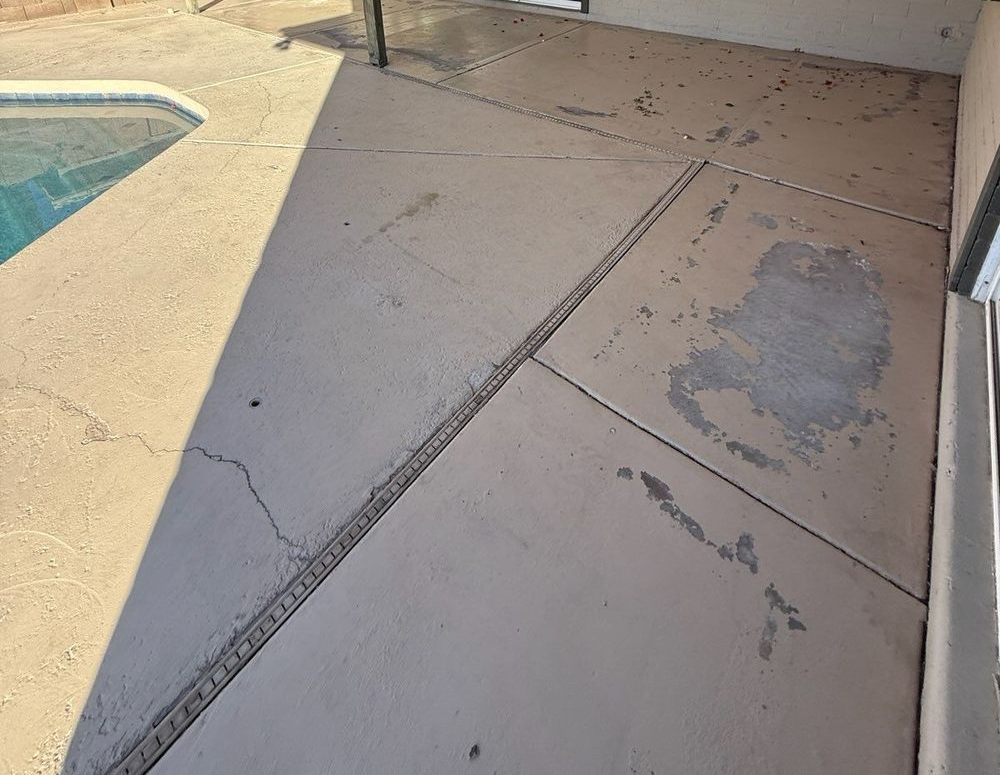 Backyard patio with pool, beige concrete, sliding glass door, shade sail.