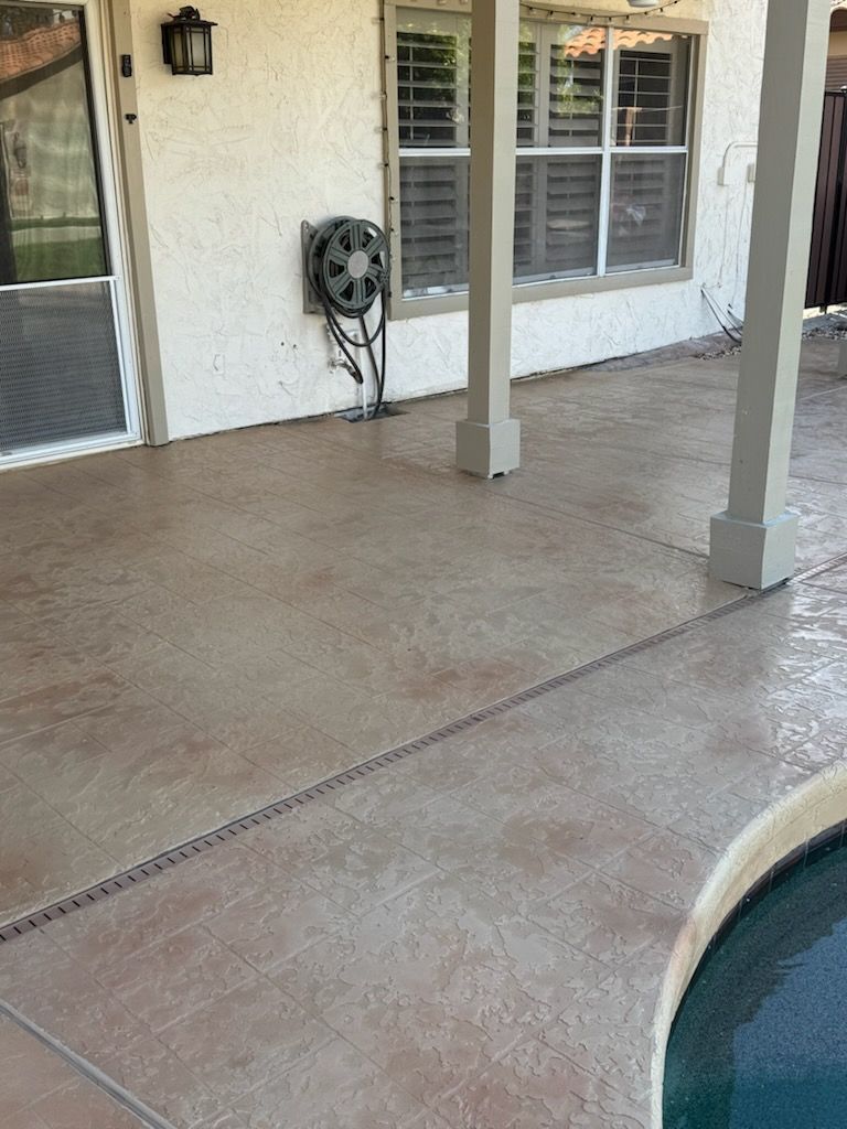 Patio with stamped concrete, pillars, and a hose reel near a window and pool.