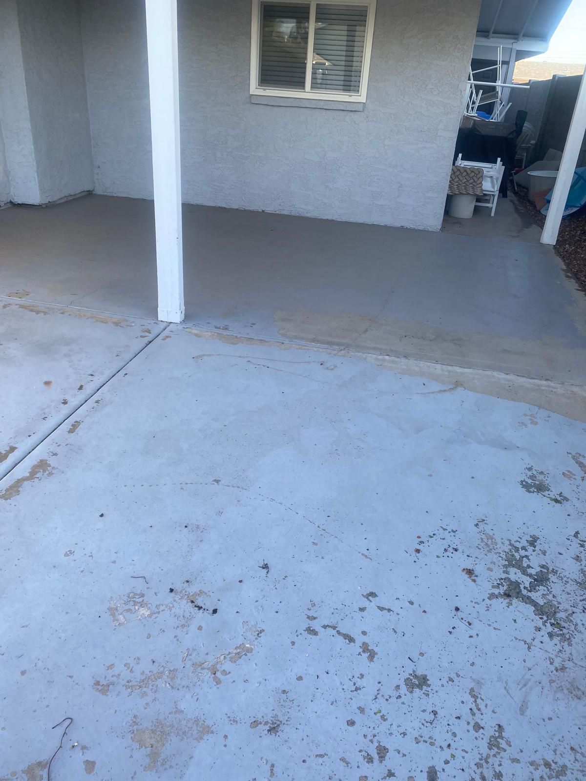 Concrete patio with support columns and a window in the background.