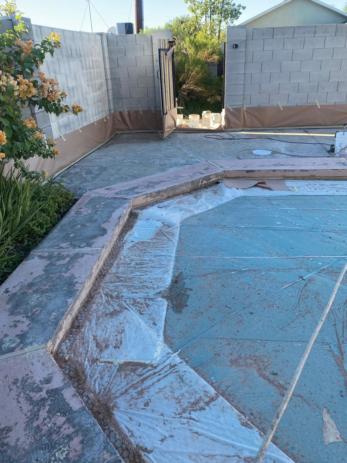 Concrete patio with light gray finish, beneath a white support column and building.