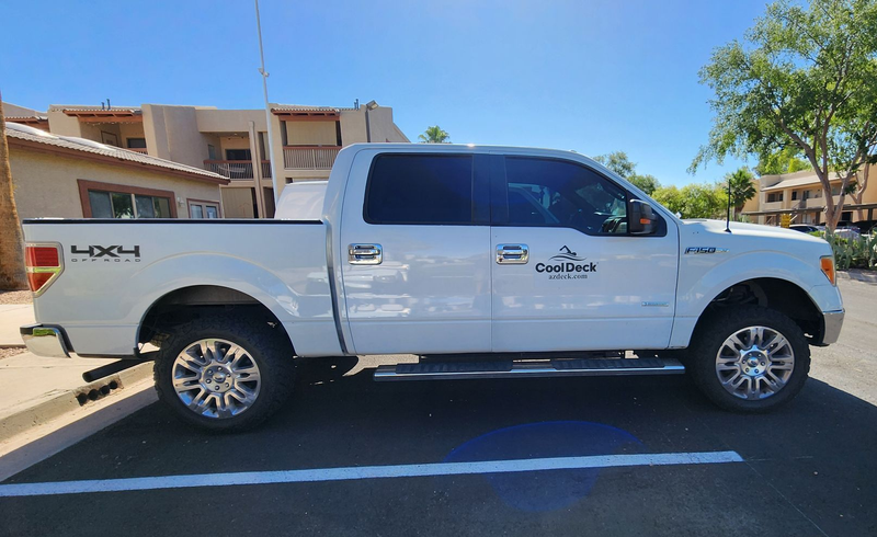 White 4x4 pickup truck parked outdoors in front of a building.