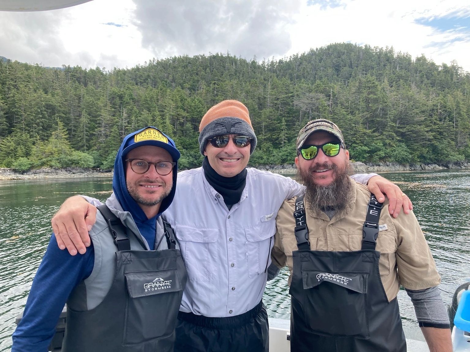 Three men are posing for a picture on a boat in the water.