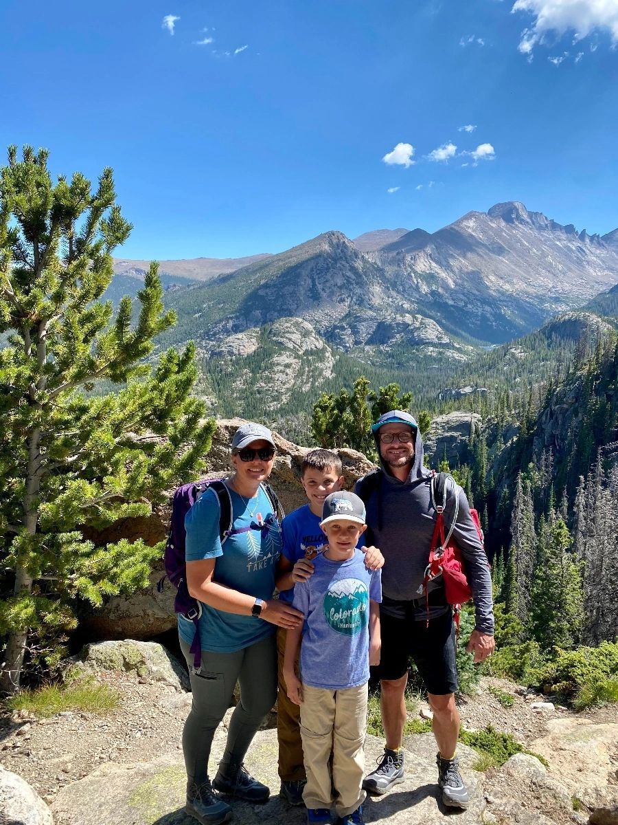 A family is posing for a picture in front of a mountain.