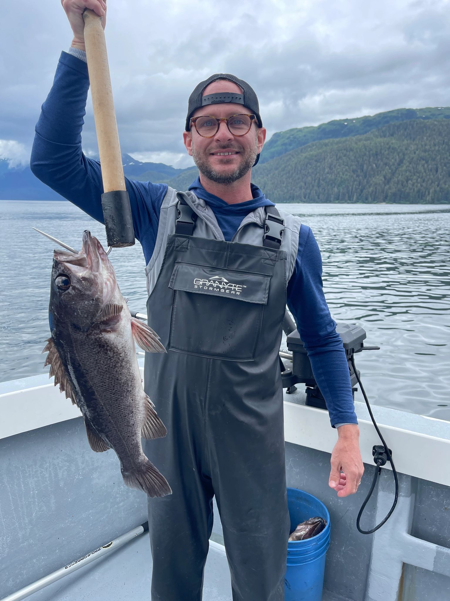 A man is holding a fish in his hand on a boat.