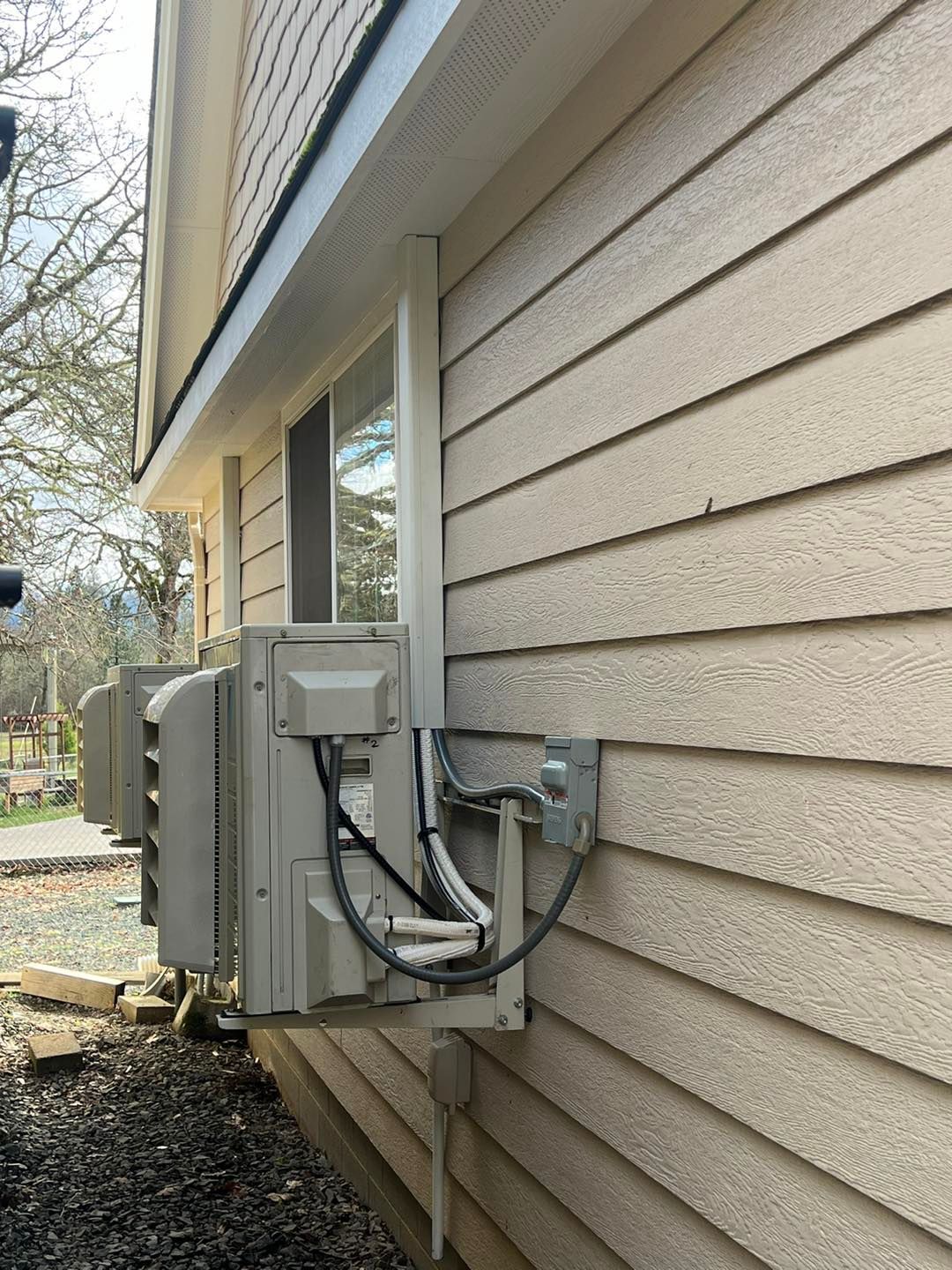 A row of air conditioners are mounted on the side of a house.