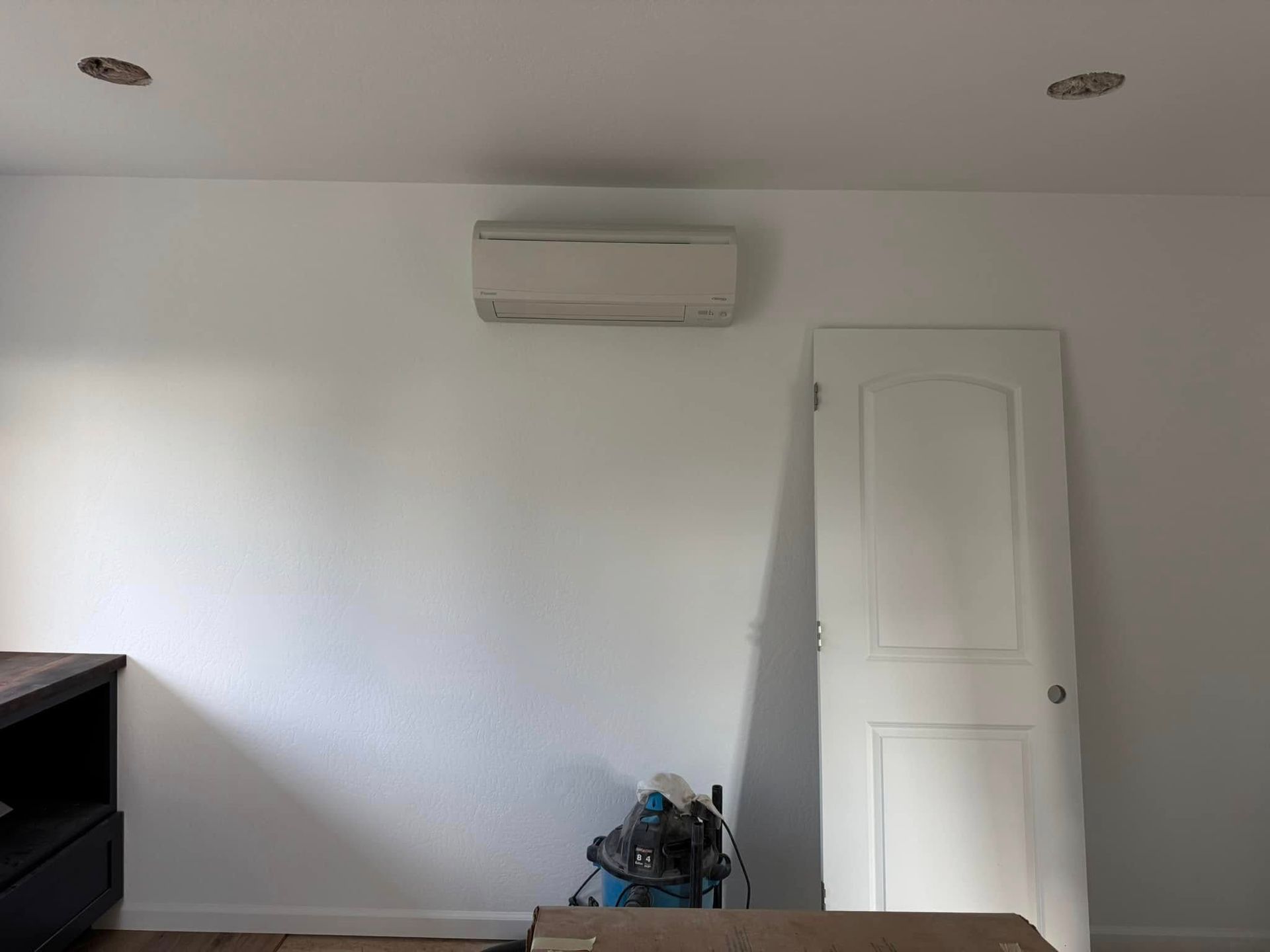 A room with white walls and a blue vacuum cleaner on the floor