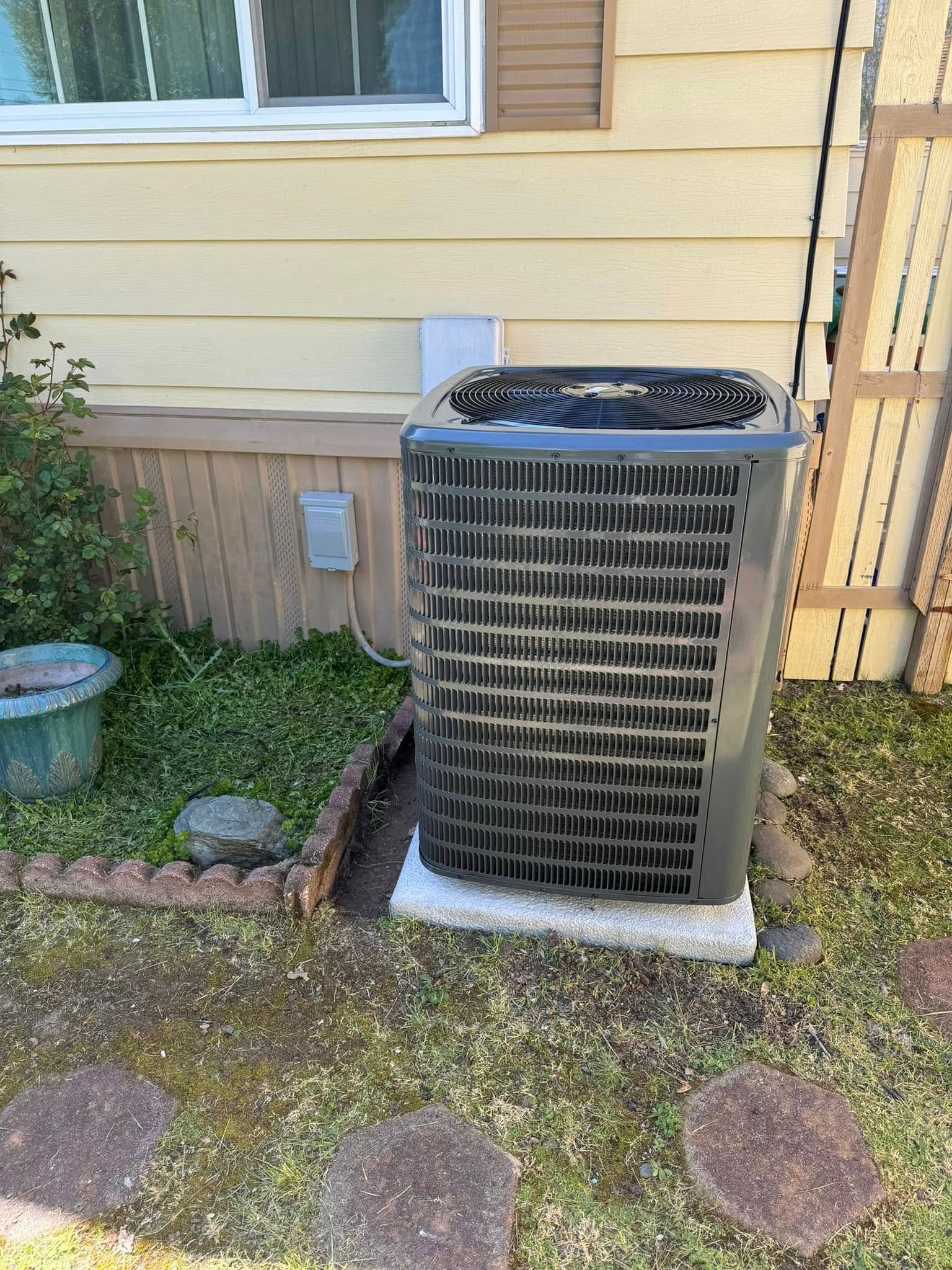 A large air conditioner is sitting on the side of a house.