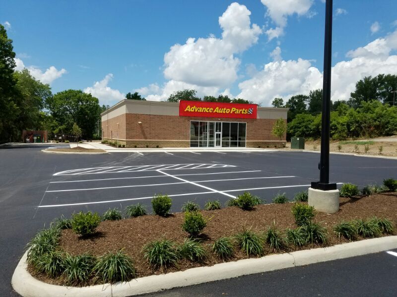 Advance Auto Parts store with empty parking lot, blue sky, and landscaping.