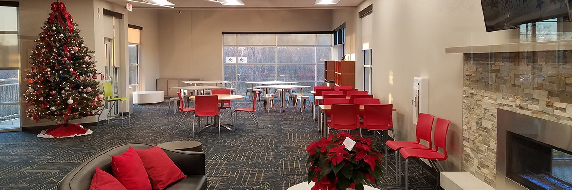 Festive room: Christmas tree, red chairs/pillows, fireplace, and large windows.