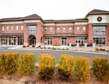 Red brick building with bushes in front.