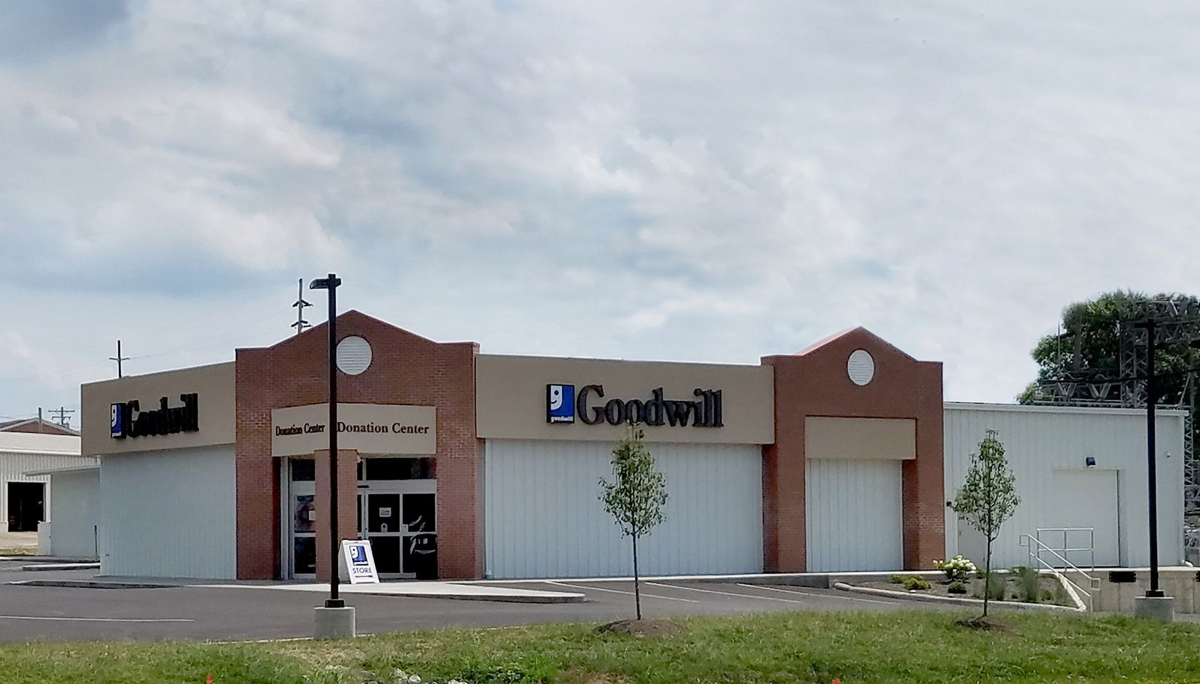 Goodwill store exterior, brick building with blue and beige signage. Light blue sky.