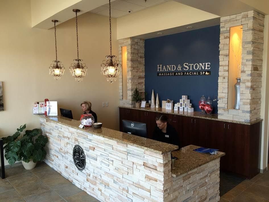 Reception area with stacked stone wall and desk, two women at the counter. 