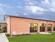 Brick building with arched windows and a lawn.