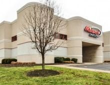 Midwest Jewelers building exterior, tan walls, red sign, small tree in front, grass and parking lot.