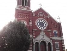 Red brick church with a tower and circular window.