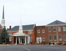 Brick building with white accents, steeple, and large windows.