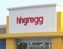 Exterior of an hhgreg storefront; red logo on white panels above yellow building facade.
