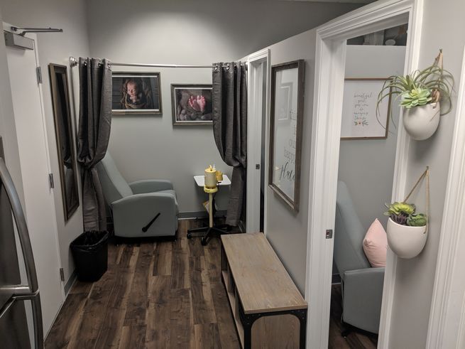 A small clinic with exam rooms, gray walls, a bench, and a recliner chair, and artwork.