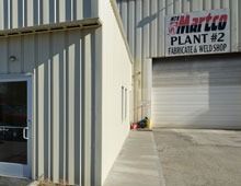 Exterior of Martco Plant #2 building with a door, window, and closed garage door.