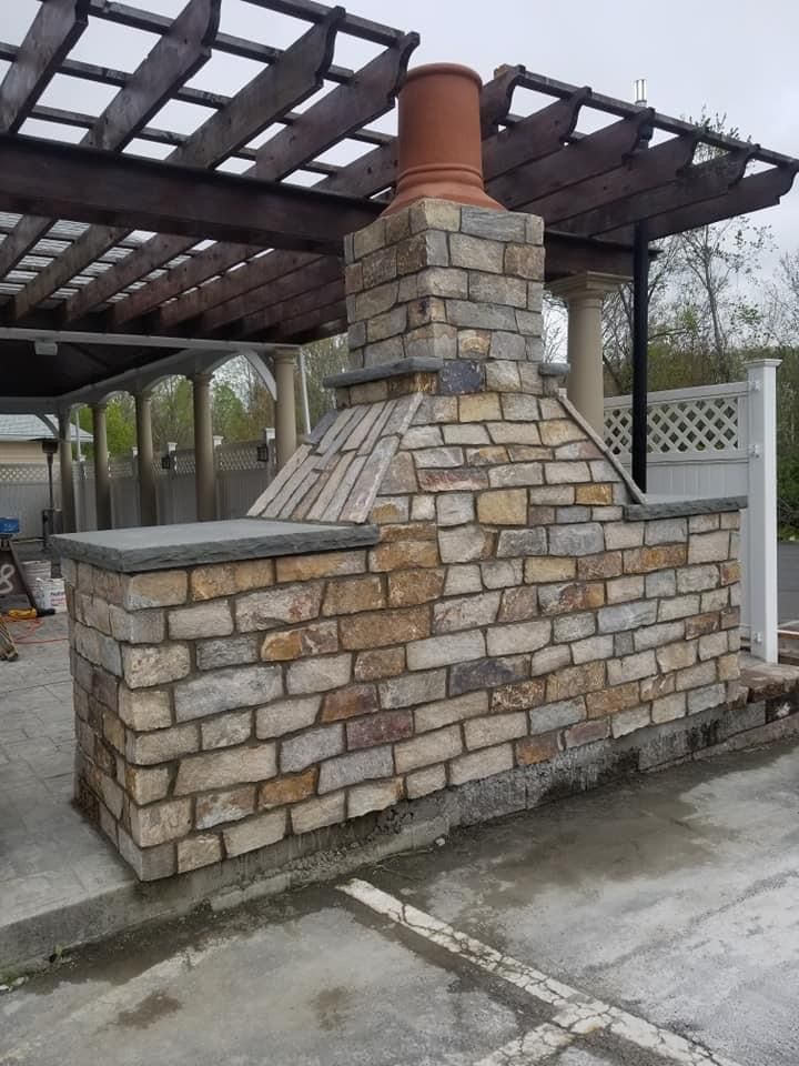 a brick fireplace is sitting under a pergola in a parking lot