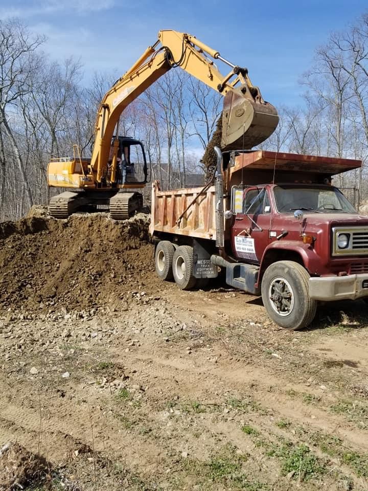 an excavator is loading dirt into a dump truck