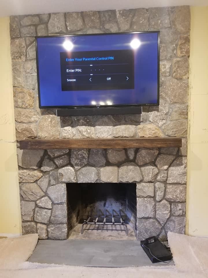 a stone fireplace with a flat-screen tv mounted above it