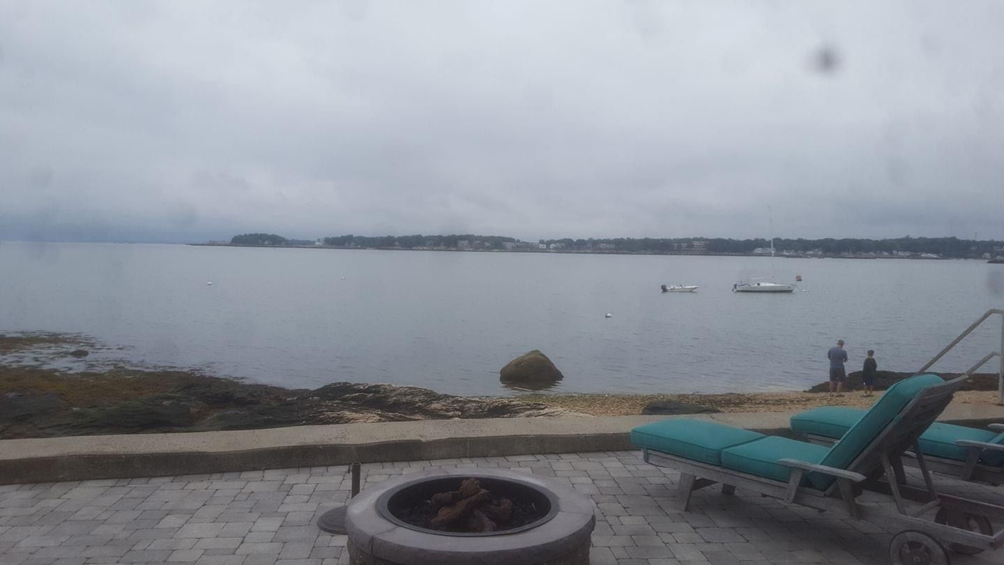 a fire pit sits on a patio next to a body of water