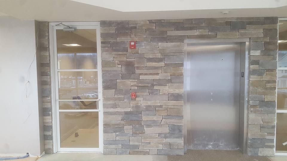 a building with a stone wall and a stainless steel door