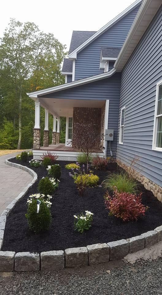 a blue house with a lush green landscape in front of it