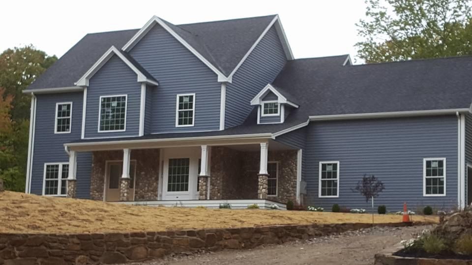 a large blue house with a black roof and white trim