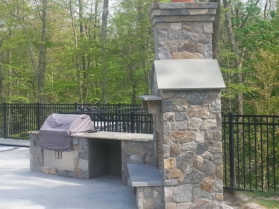 a grill is sitting in front of a stone chimney