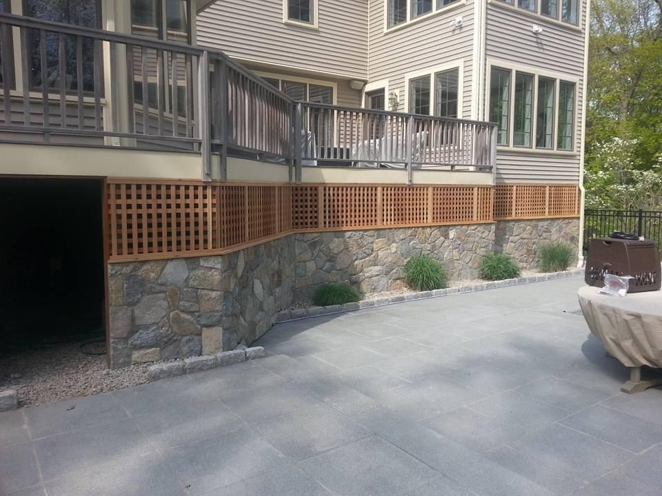 a house with a large deck and a stone wall