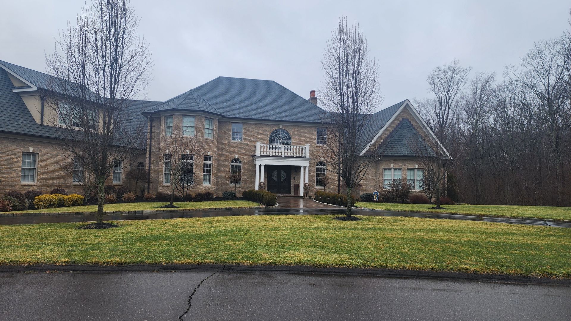 a large brick house with a blue roof sits on a lush green lawn