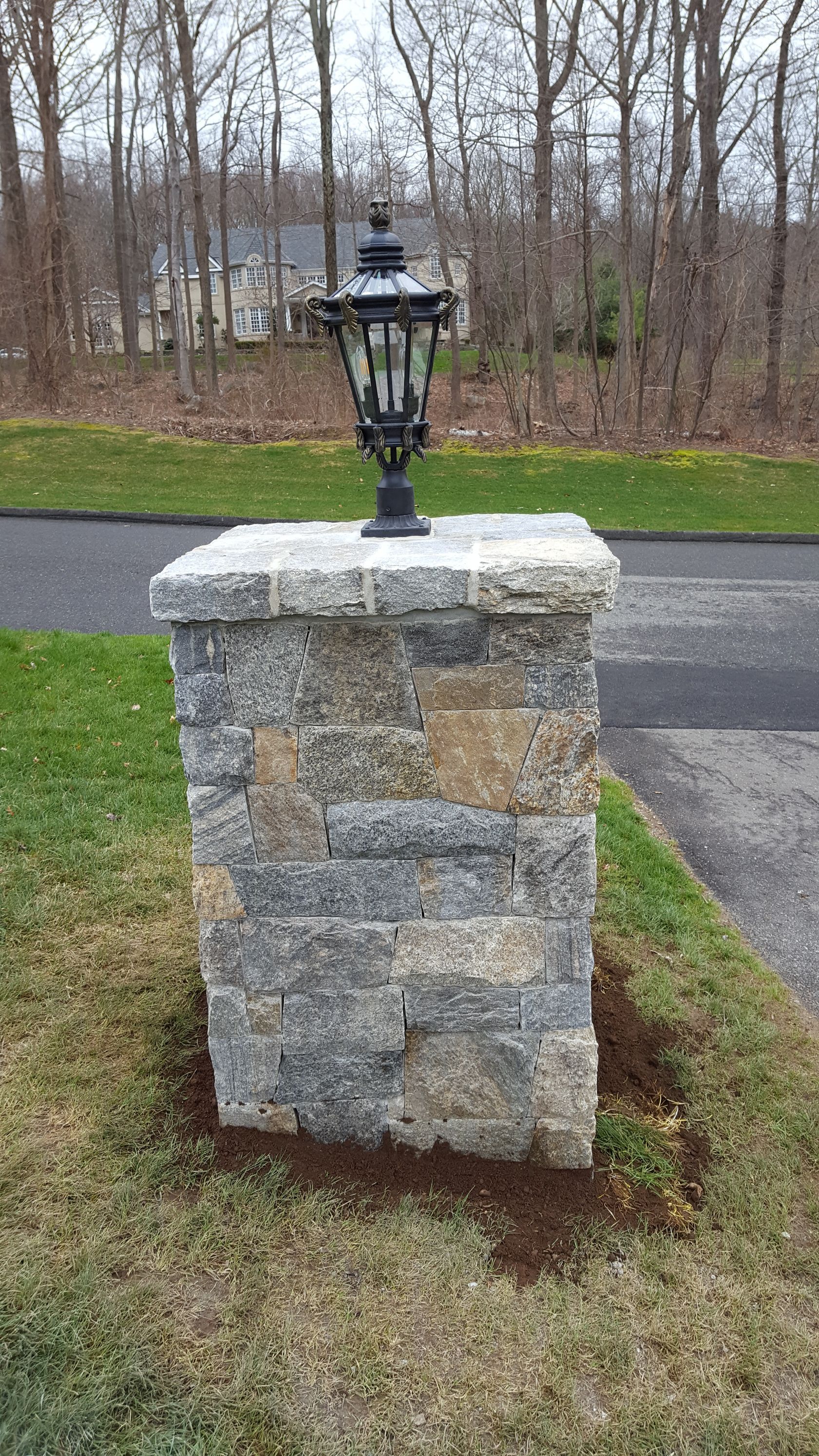 a lamp post sits on top of a stone pillar in the grass