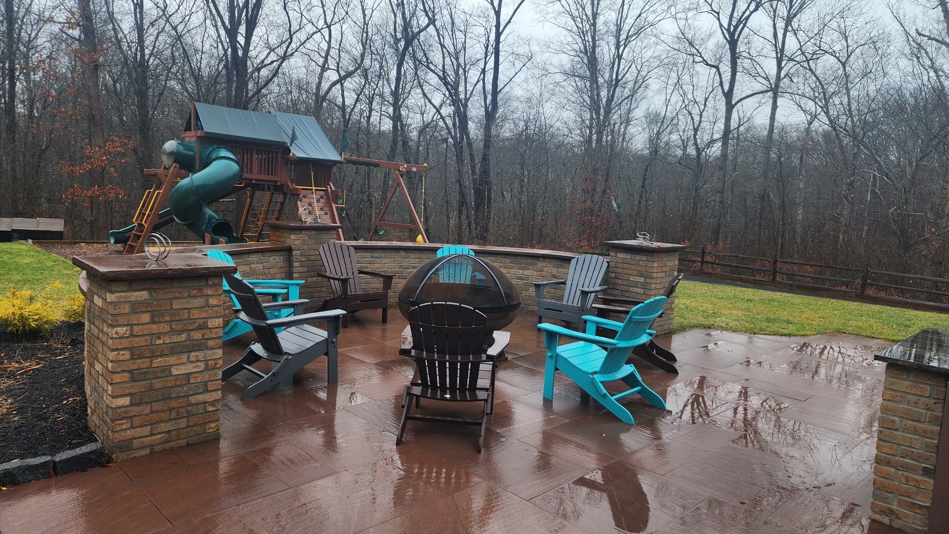 a patio with chairs and a playground in the background on a rainy day