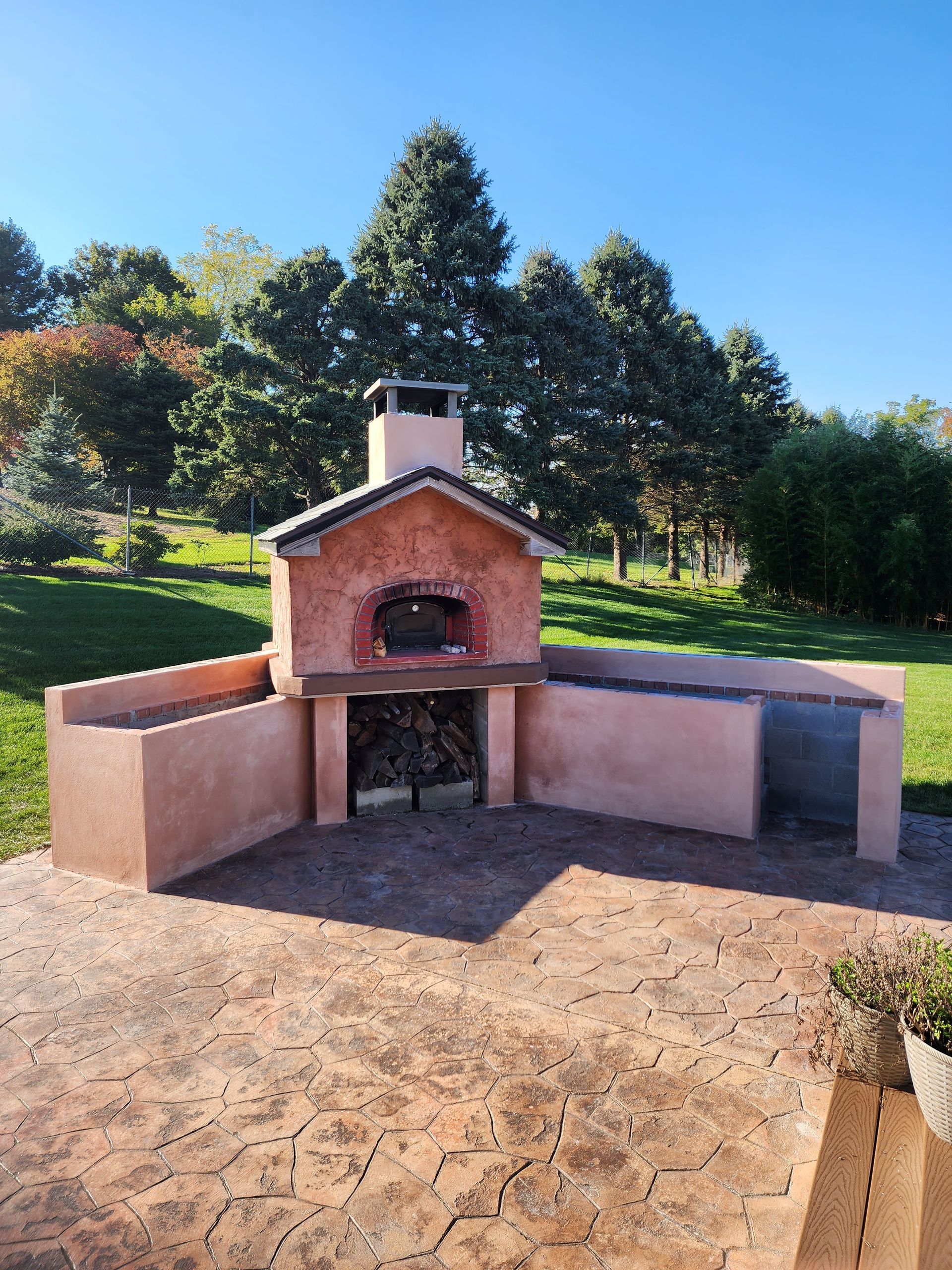 a brick oven is sitting on a patio with trees in the background