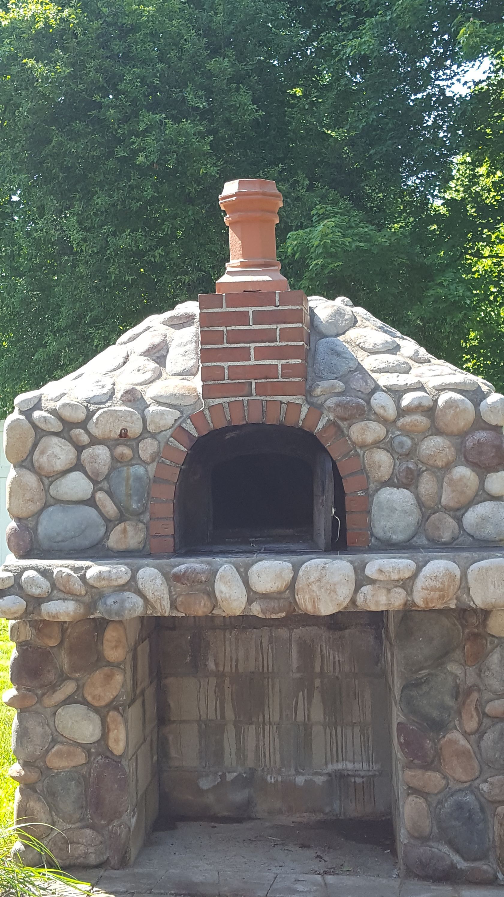 a brick oven built into a stone wall with a chimney