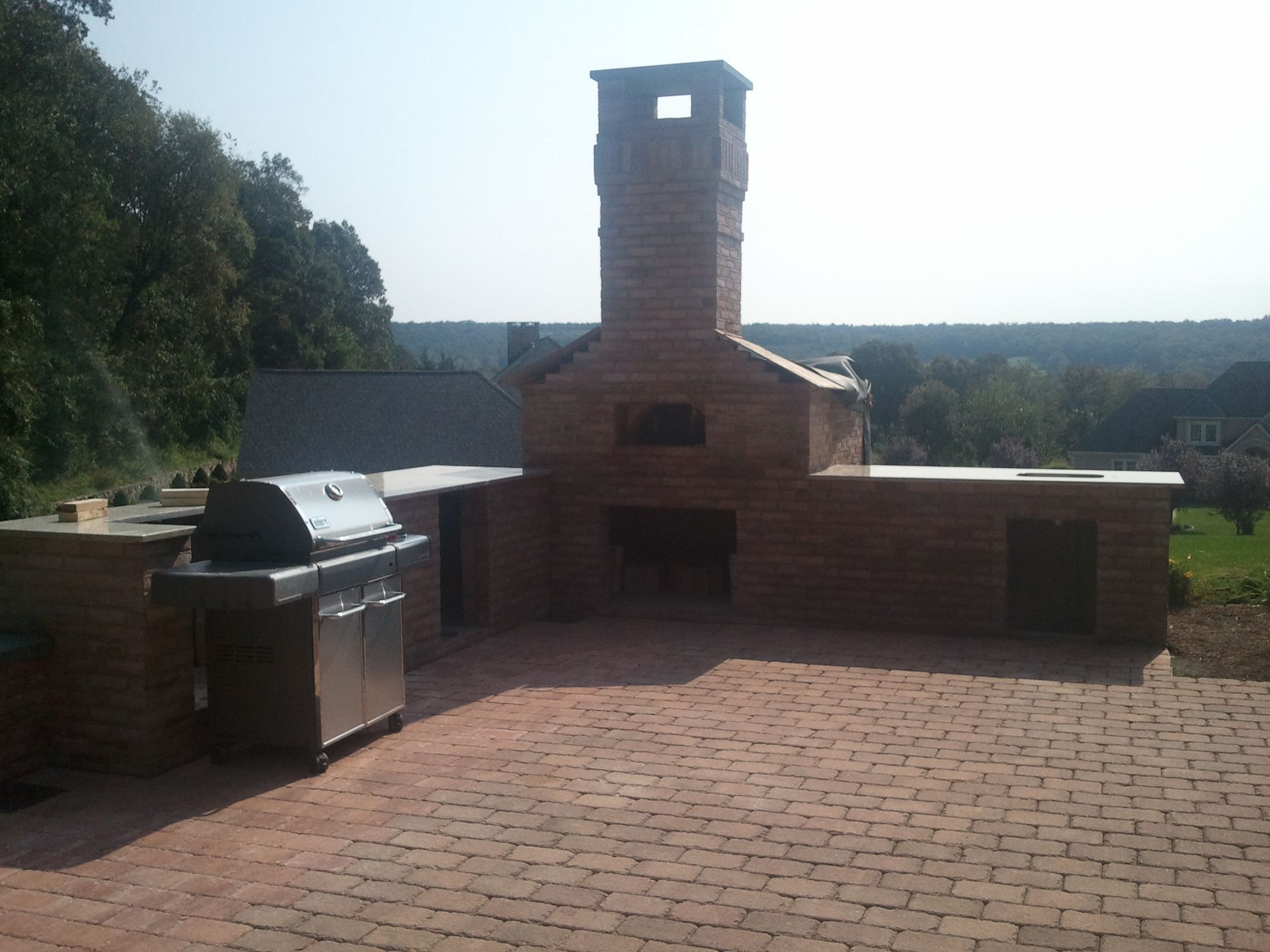 a brick patio with a grill and a chimney