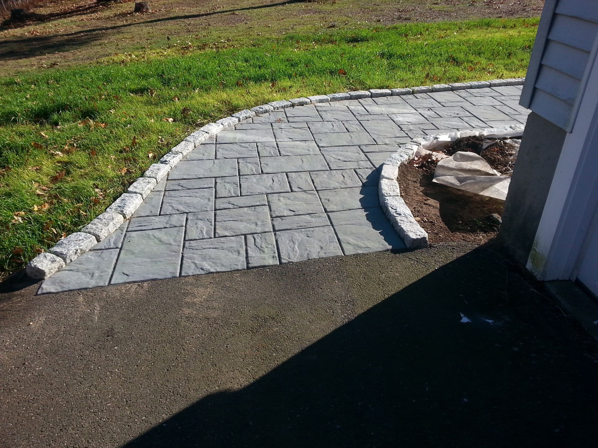 a brick walkway leading to a grassy area next to a house