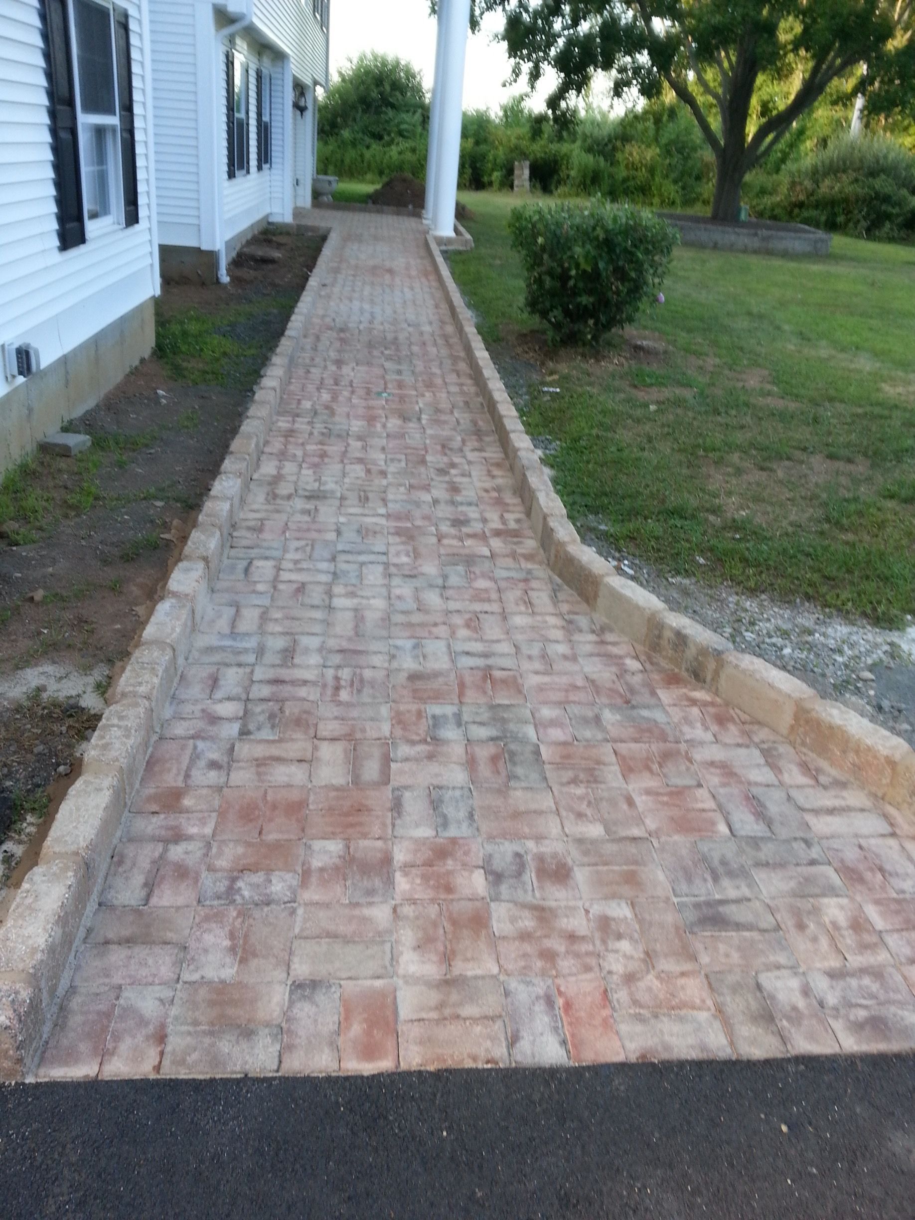 a brick walkway leading to a white house