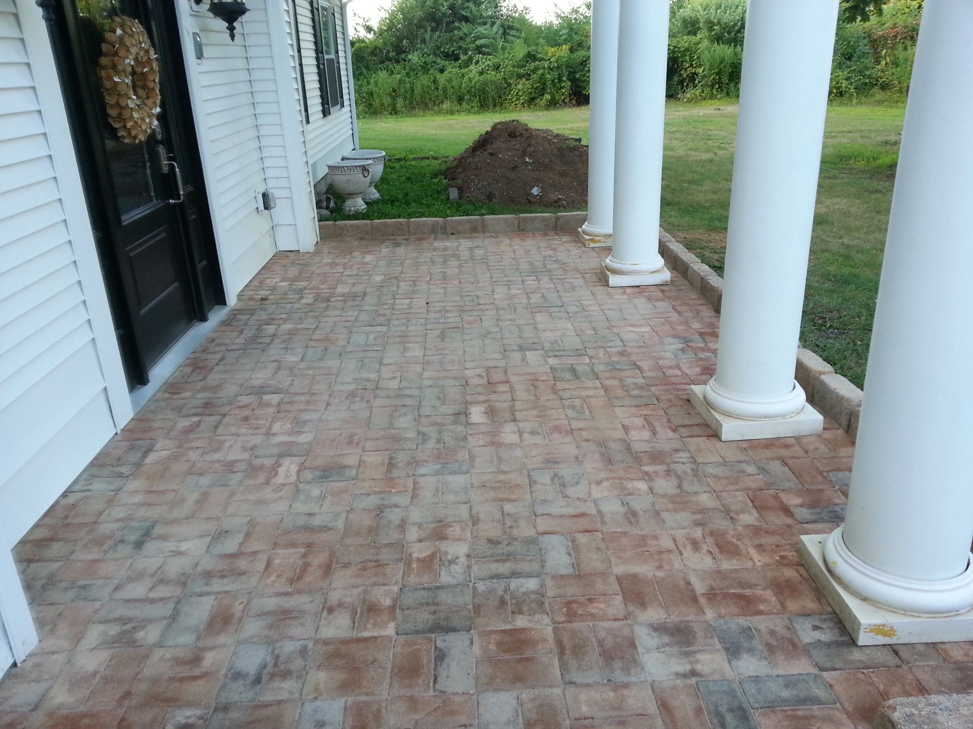 a brick porch with columns and a wreath on the door