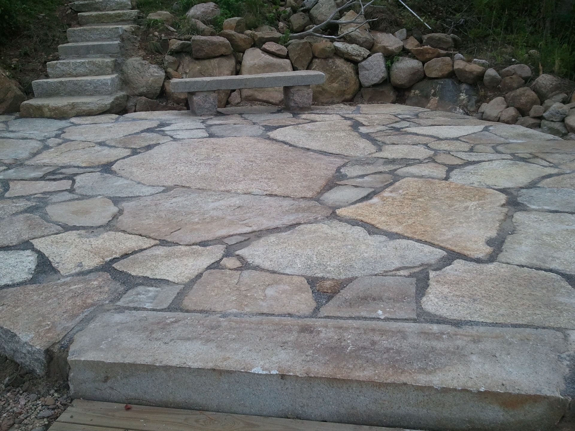 a stone walkway with stairs and a bench in the middle