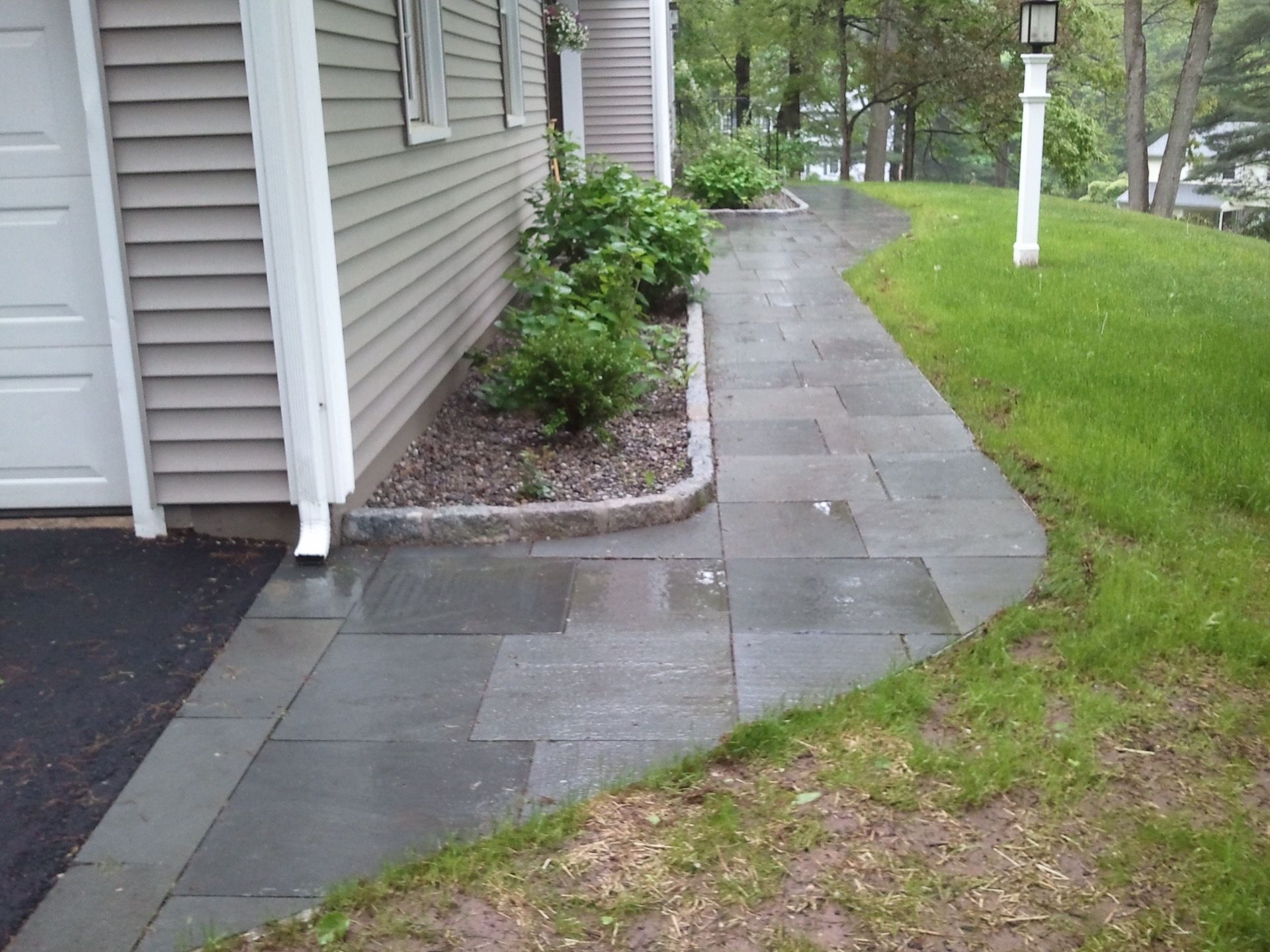 a walkway leading to a house with a white garage door