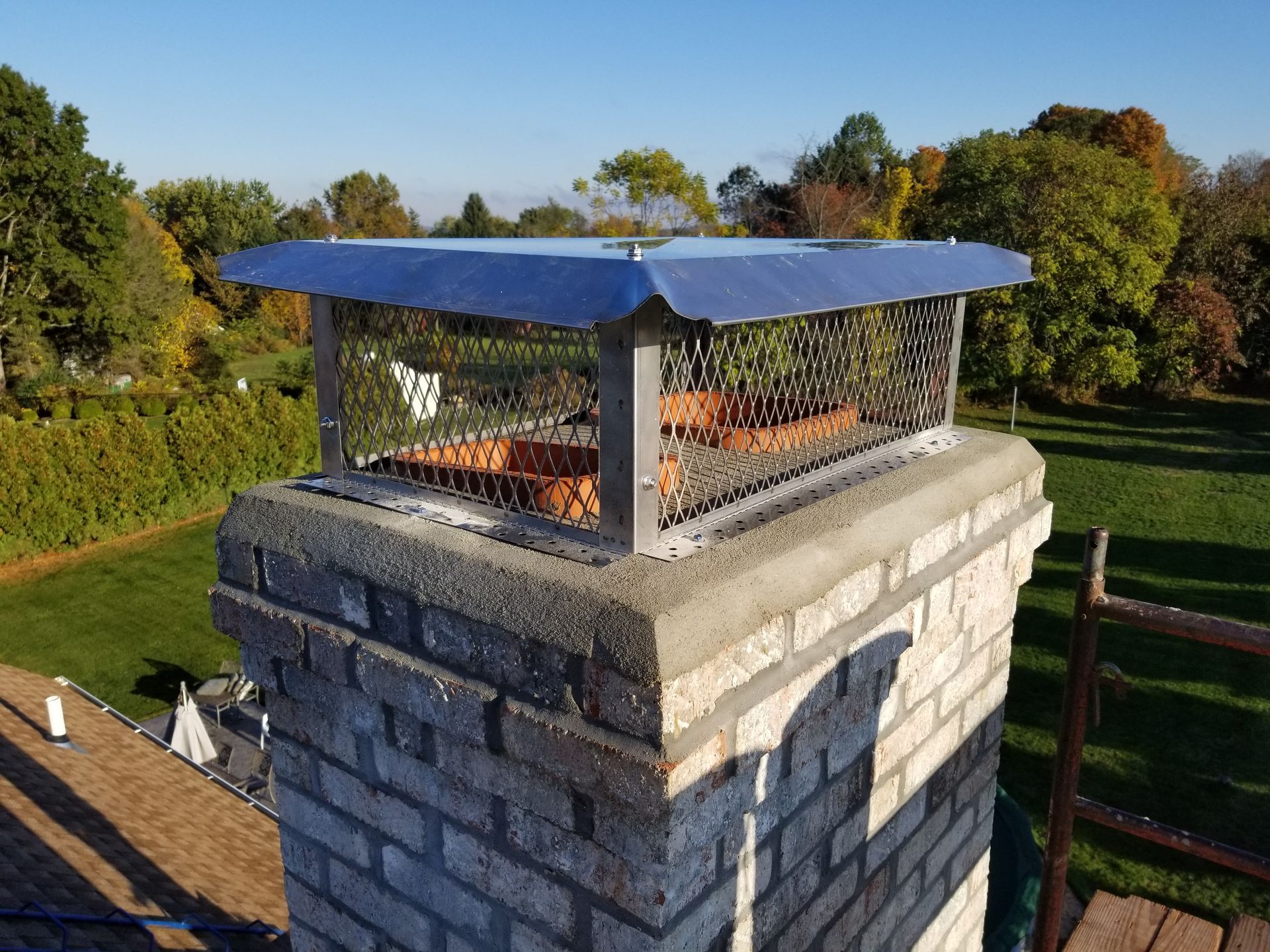a brick chimney with a metal cover on top of it